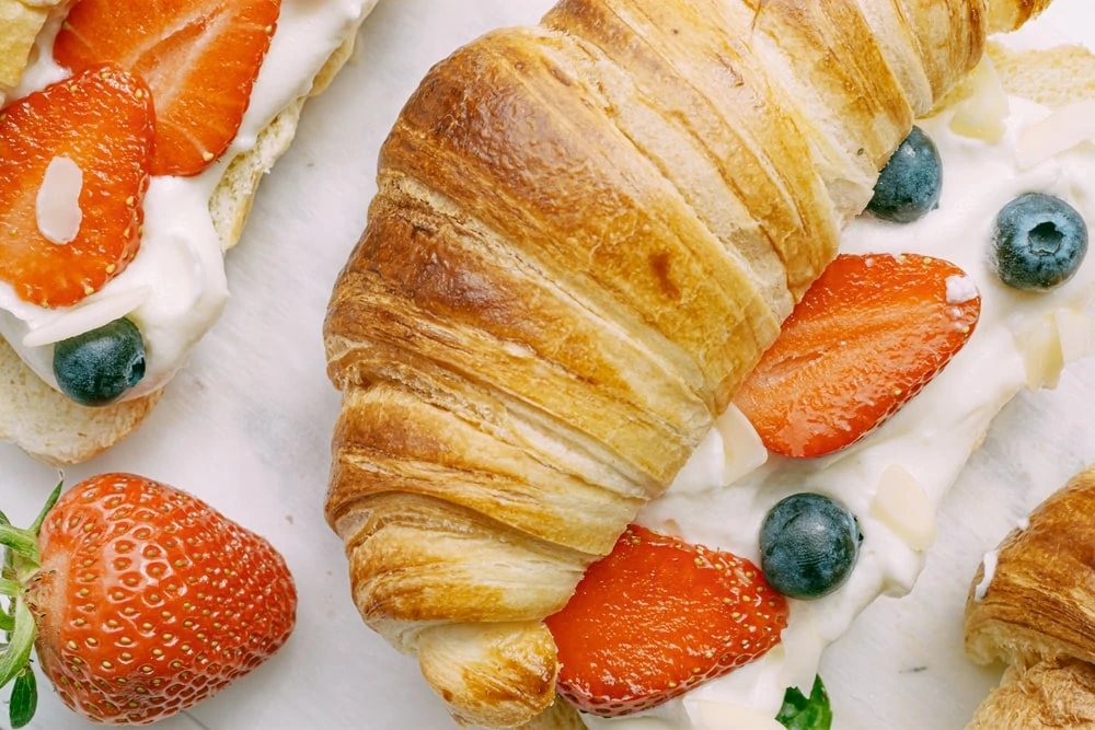 croissant with strawberries scattered around it| Image credit: insanelygoodrecipes.com